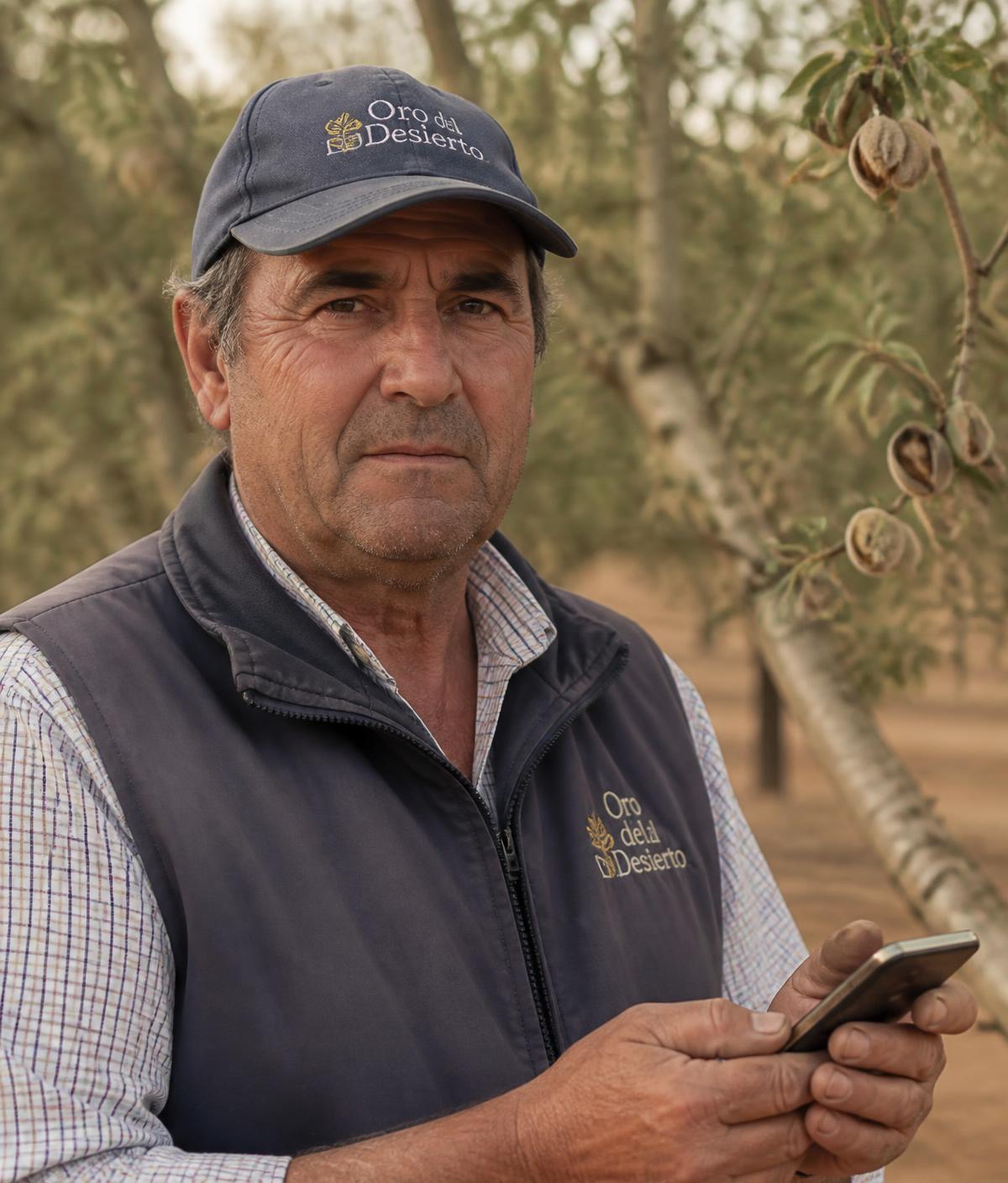 Agricultor registrando un tratamiento desde el móvil en una parcela de almendro
